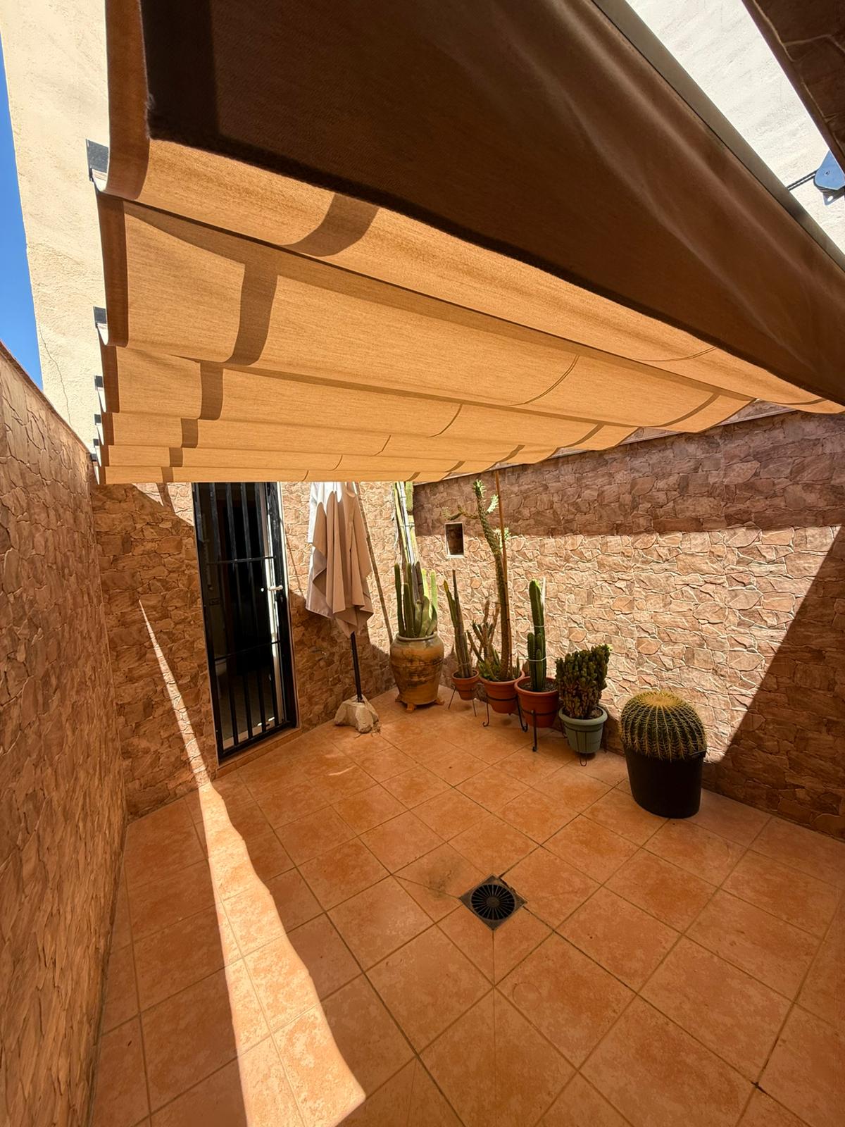 Toldo extensible sobre patio con cactus